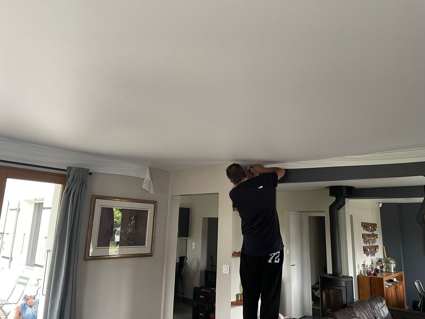 Patrice Sanchez, artisan L'Autre Plafond, en train de poser une toile tendue au plafond